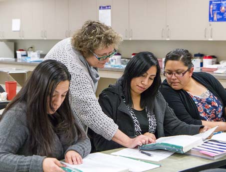 Instructor points to something on a student's page while working with a group.