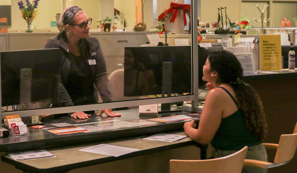 Student speaks to college employee in an admin office. 