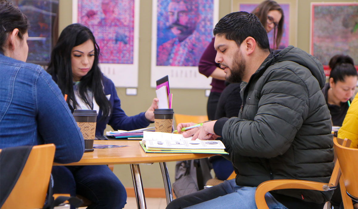 Students working in their text books while drinking coffee.