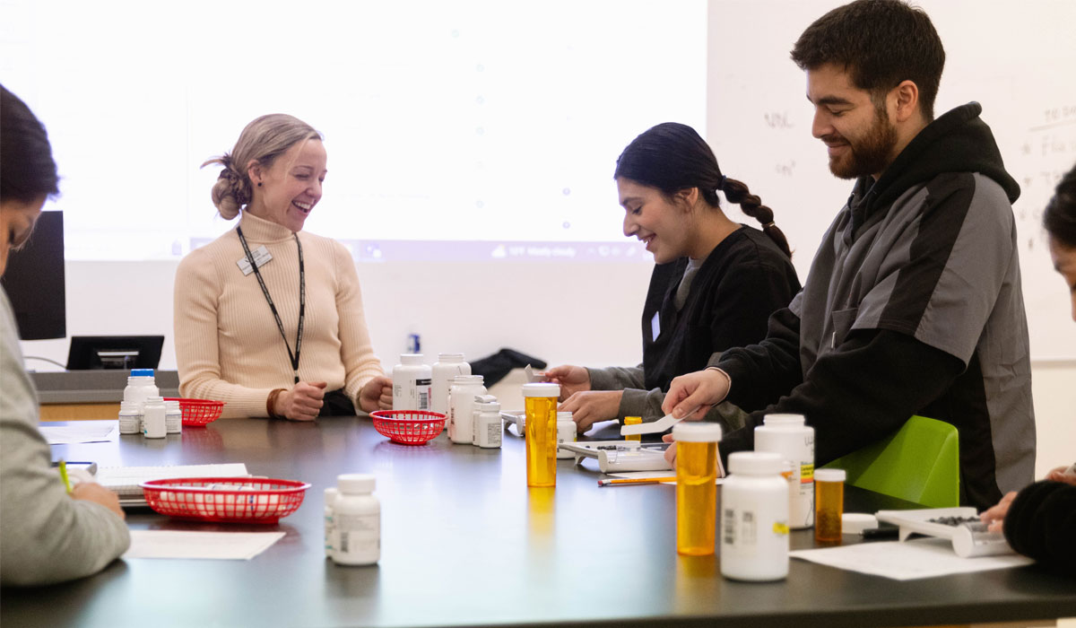 Pharmacy instructor helps students with hands on assignment.