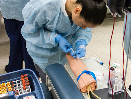 YVC Student practices taking blood on a test device during class. 