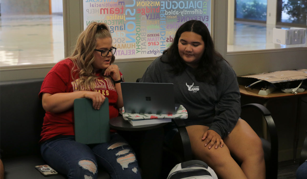 Two female students work on a computer together. 