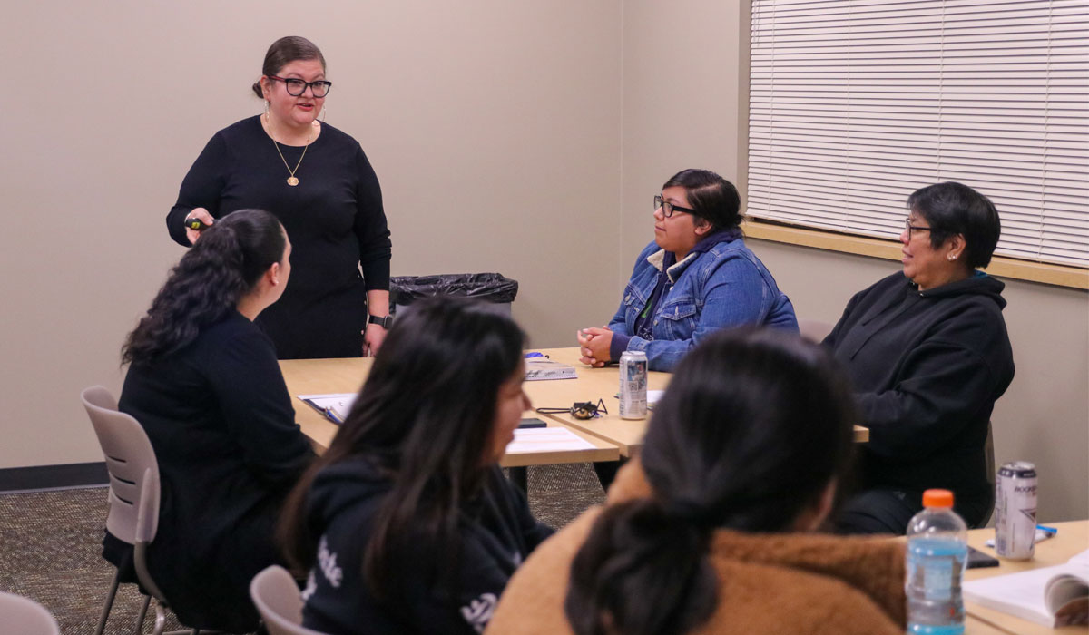 YVC education professor speaking to table of students. 