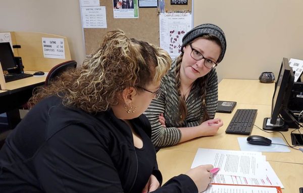 Teacher works with student at a table. 