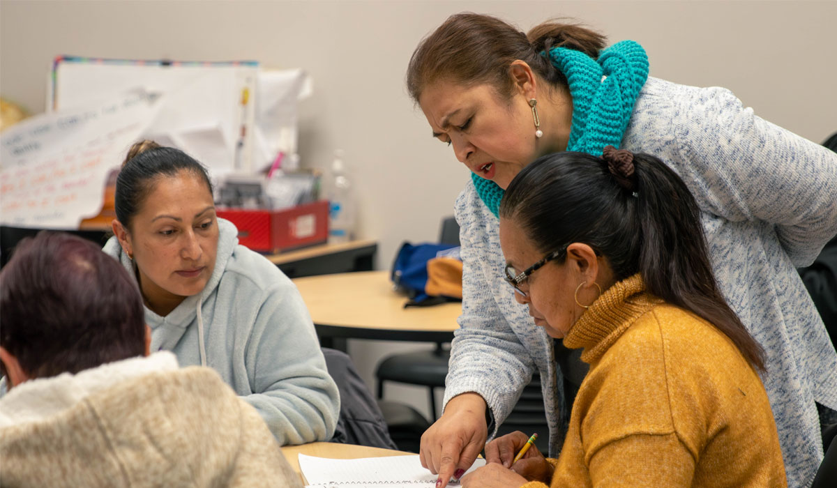 Instructor points at students paper as she works with her class. 