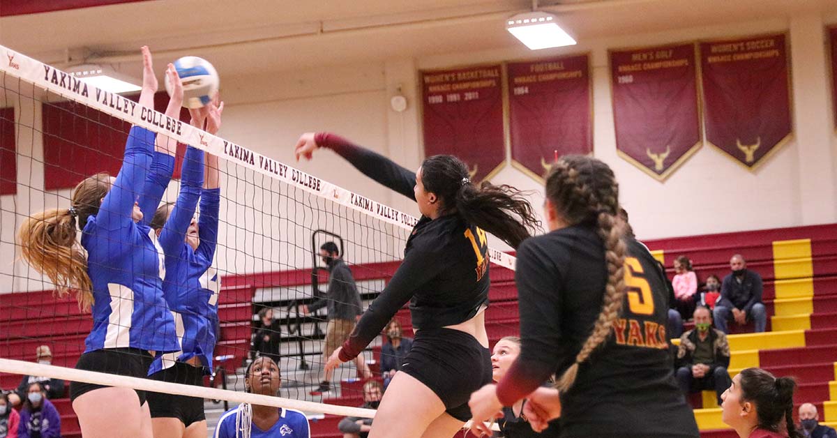 Female volleyball player spikes ball