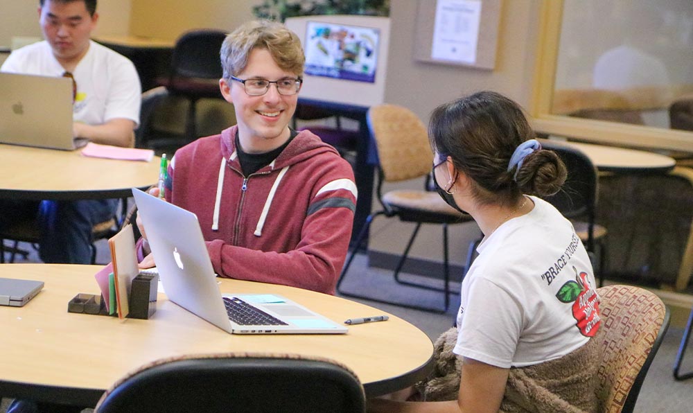 Student tutor talks with student at table