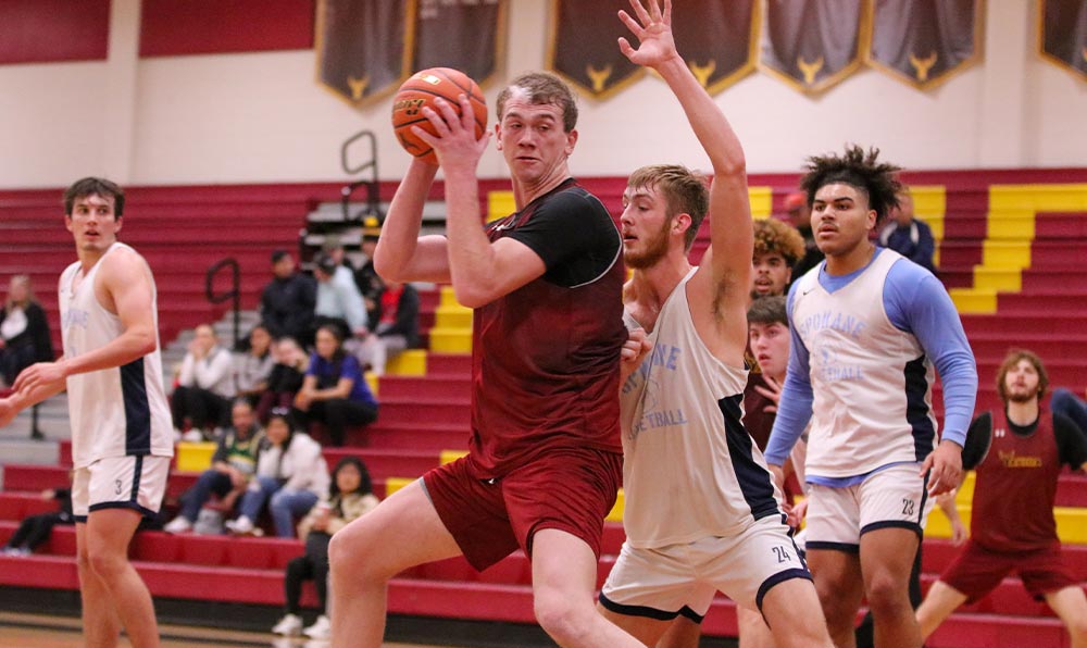 Male basketball player posts up opponent