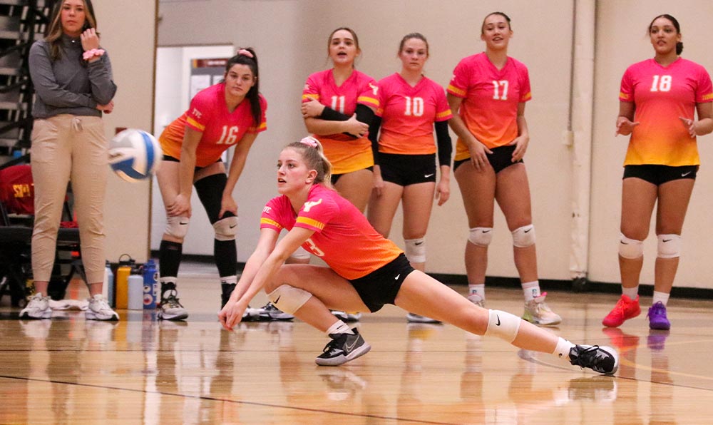 Female volleyball player digs ball