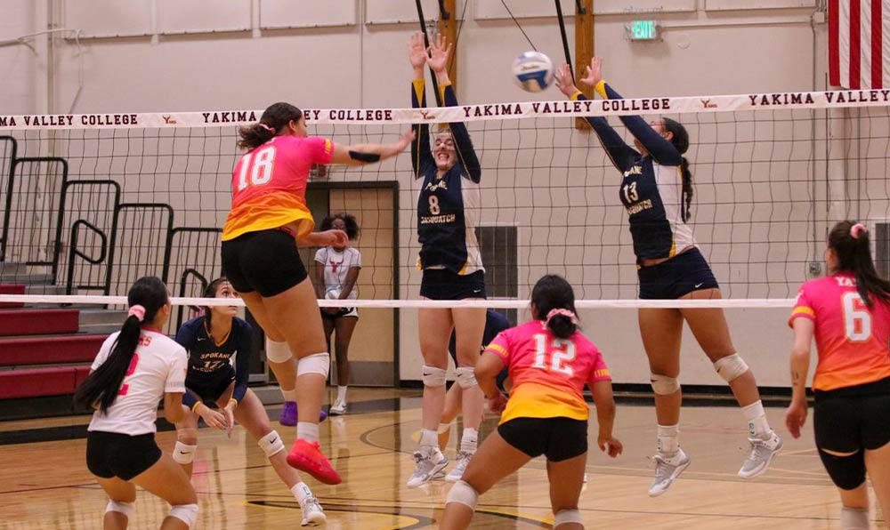 Female volleyball player spikes ball