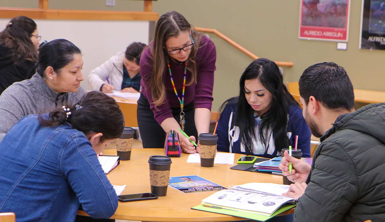 Instructor talks to students at table