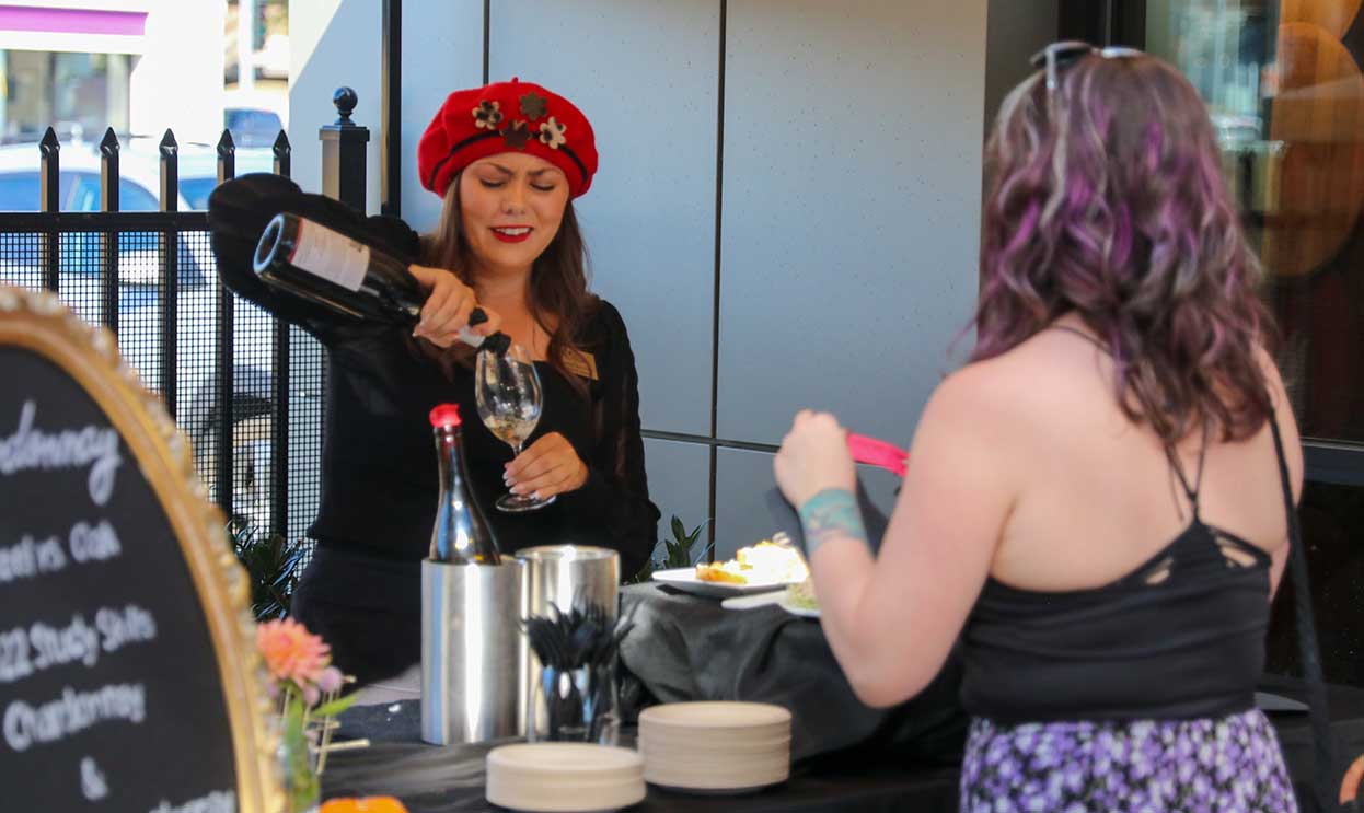 Volunteer pours wine during the French Market event