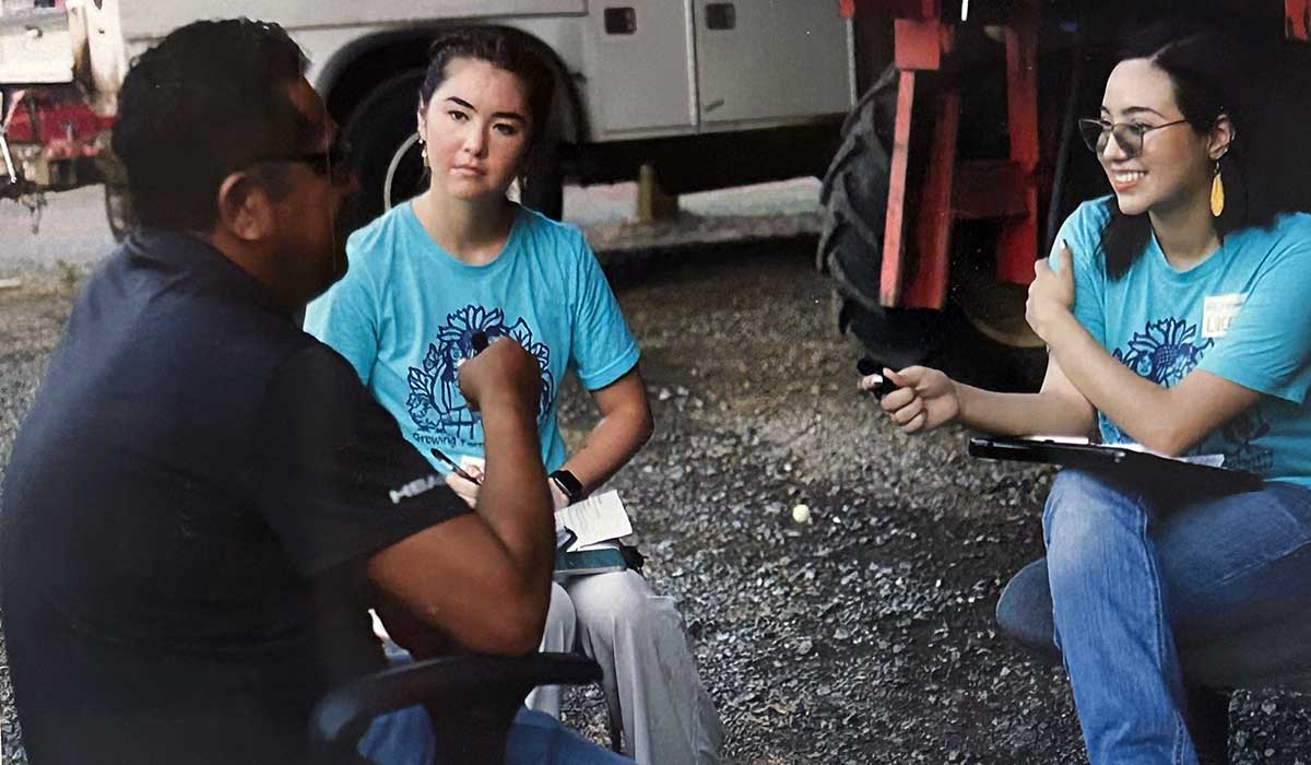 Mendez along with another fellow speak with a farmworker