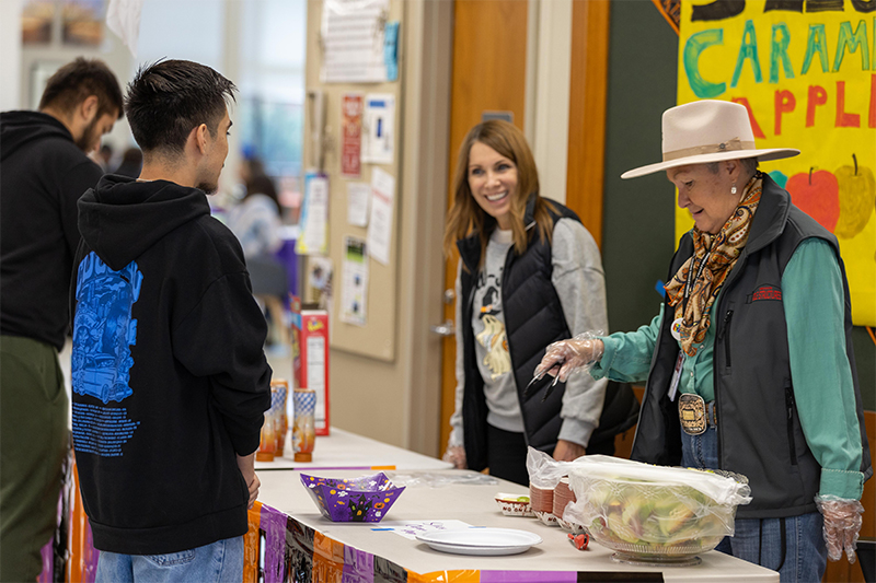 YVC leaders serve caramel apples to students during Halloween event