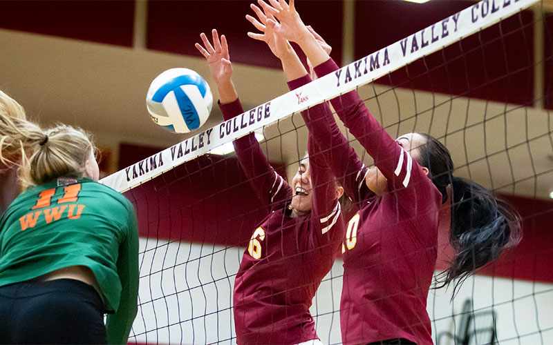 Two YVC volleyball players block spike attempt