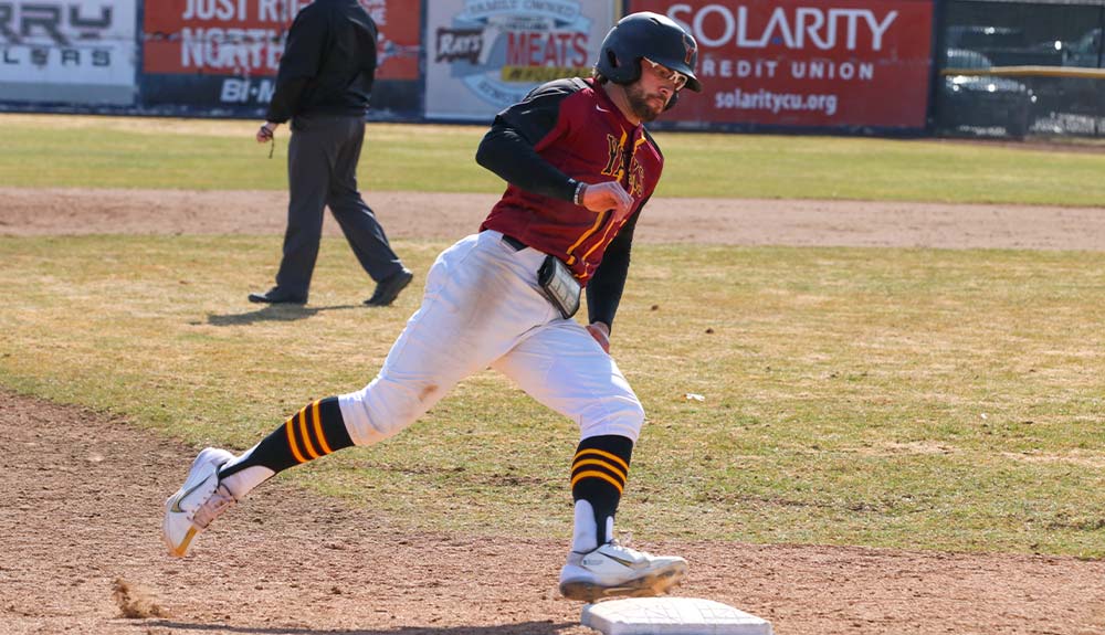 Baseball player runs past third base.