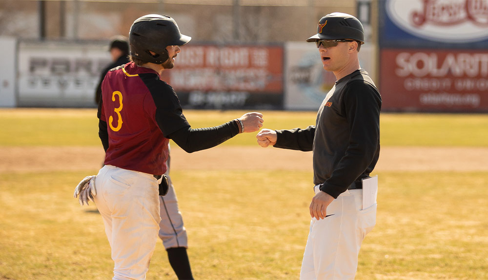 Baseball coach and player bump fists