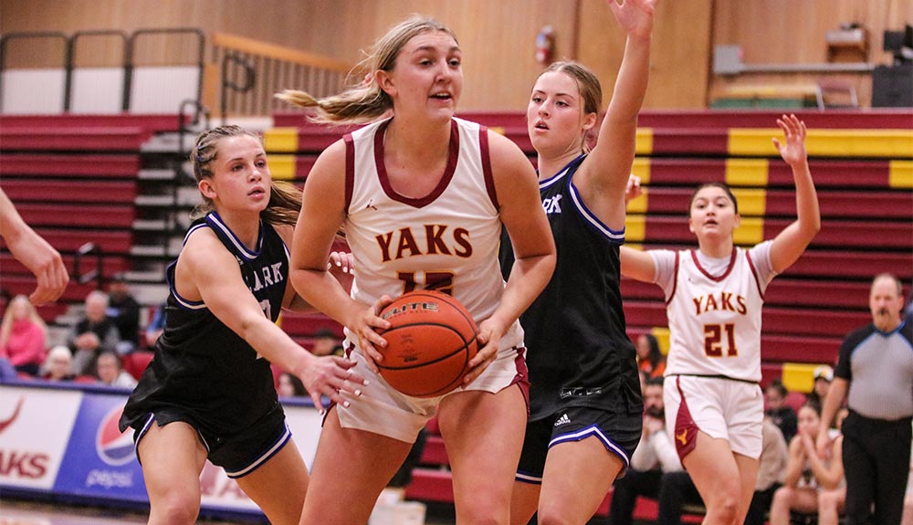 Female basketball player with ball guarded by two opponents