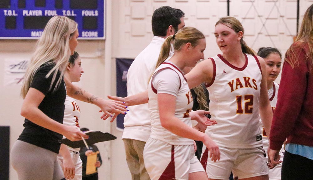 Women's basketball player high fives teammate.