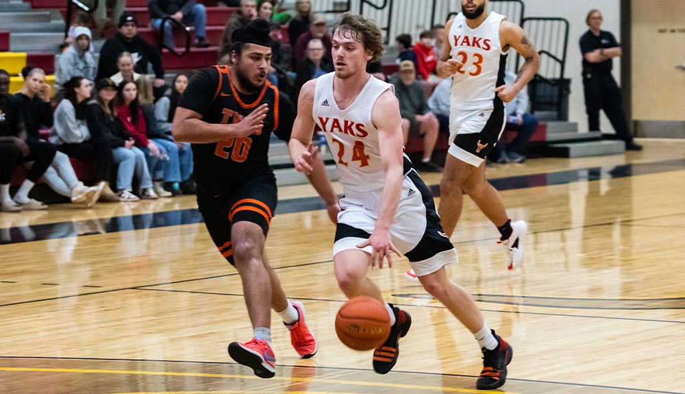 Yaks men's basketball player drives past defender