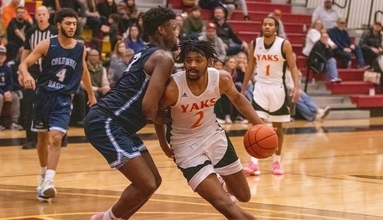 YVC men's basketball player drives around a defender