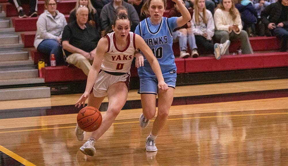 Female basketball player drives past defender along baseline