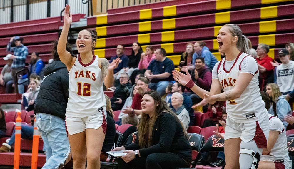 Female basketball players cheer from sidelines