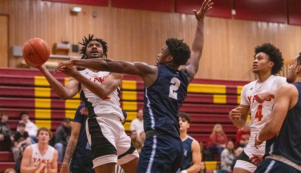 Male basketball player attempts shot while being defended