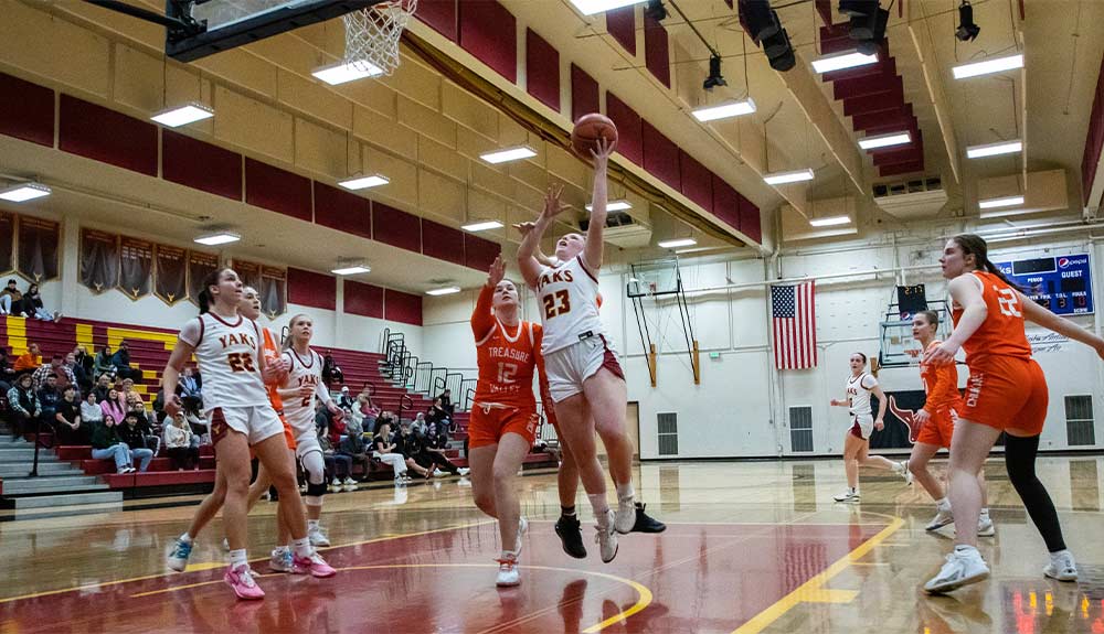 Female basketball player attempts layup.