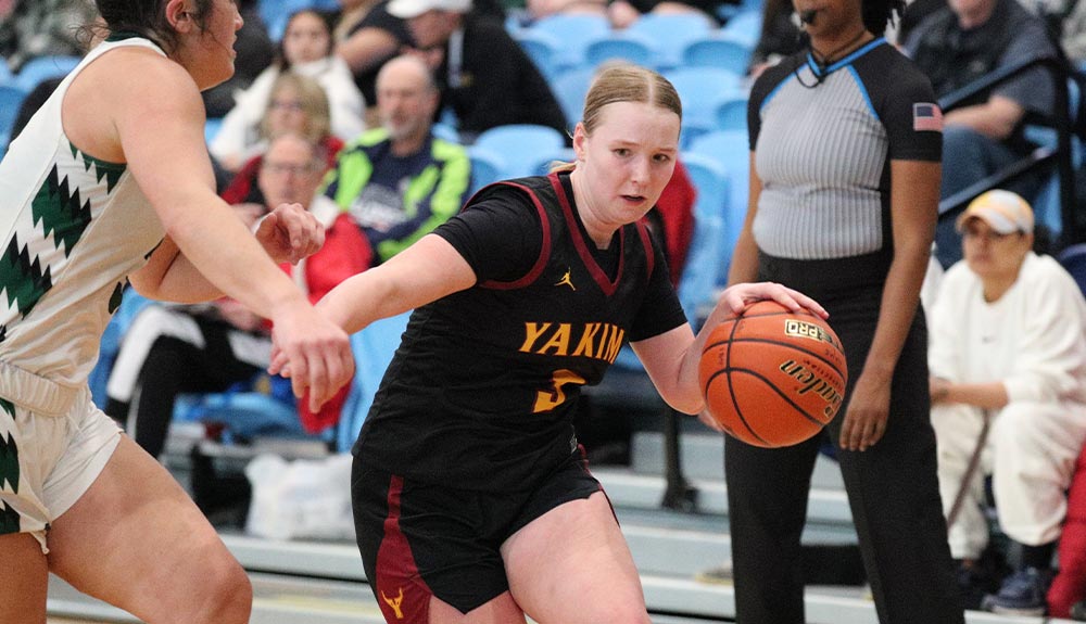 Female basketball player dribbles past defender