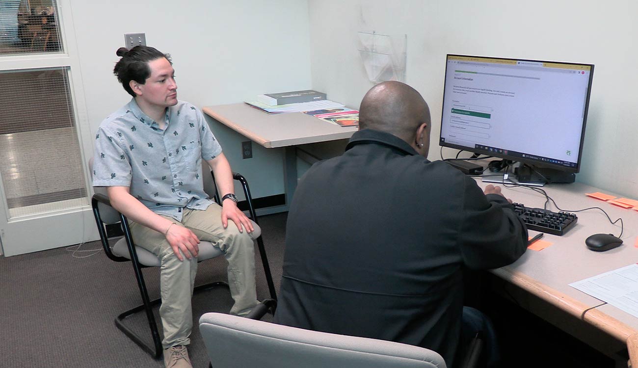 Two people at desk with computer