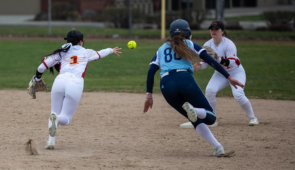 Softball player tosses ball to teammate at base