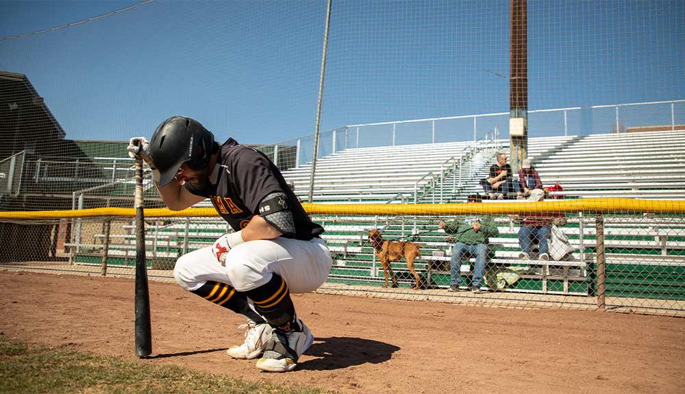 Baseball player with bat squats