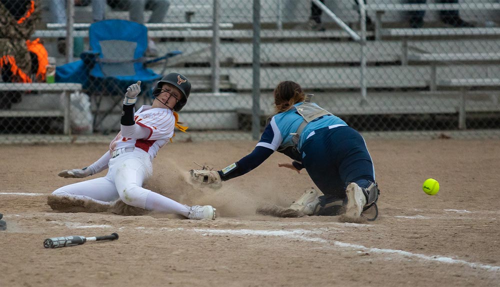 Softball player slides into home plate