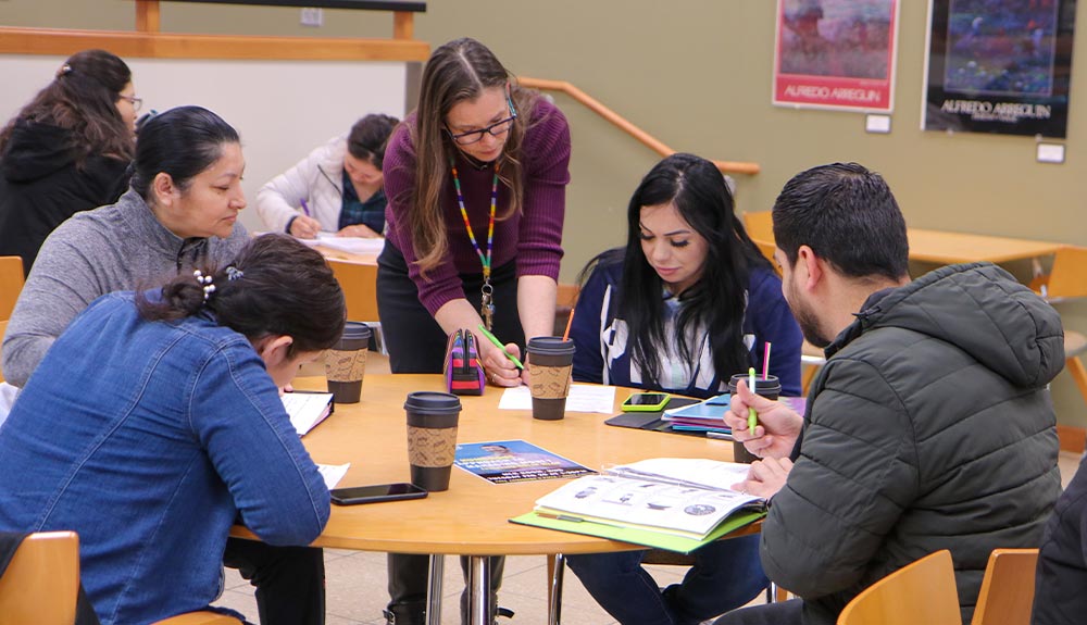 Instructor talks to students sitting around table