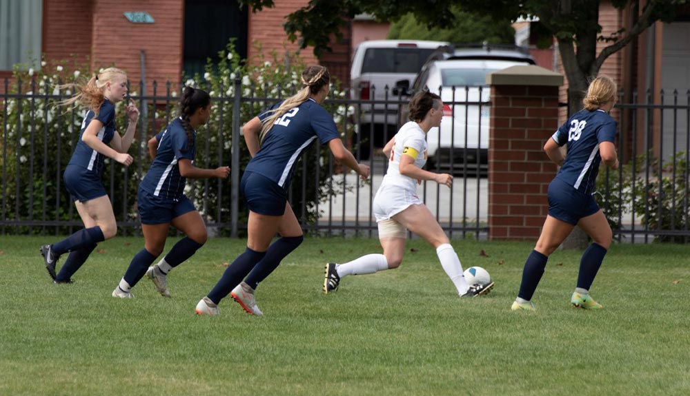 Soccer player with ball surrounded by defenders