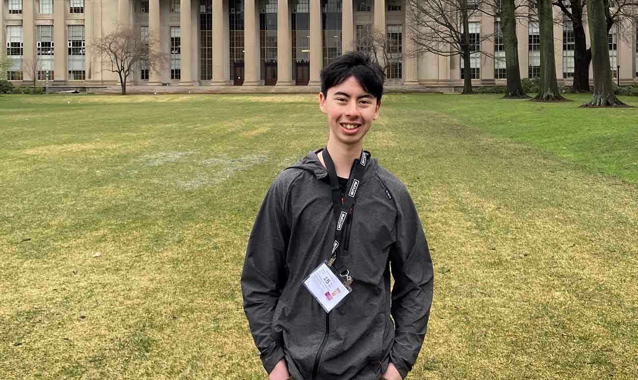 Jaden Gaudet poses for a photo on MIT's campus in front of the Great Dome building in Killian Court.