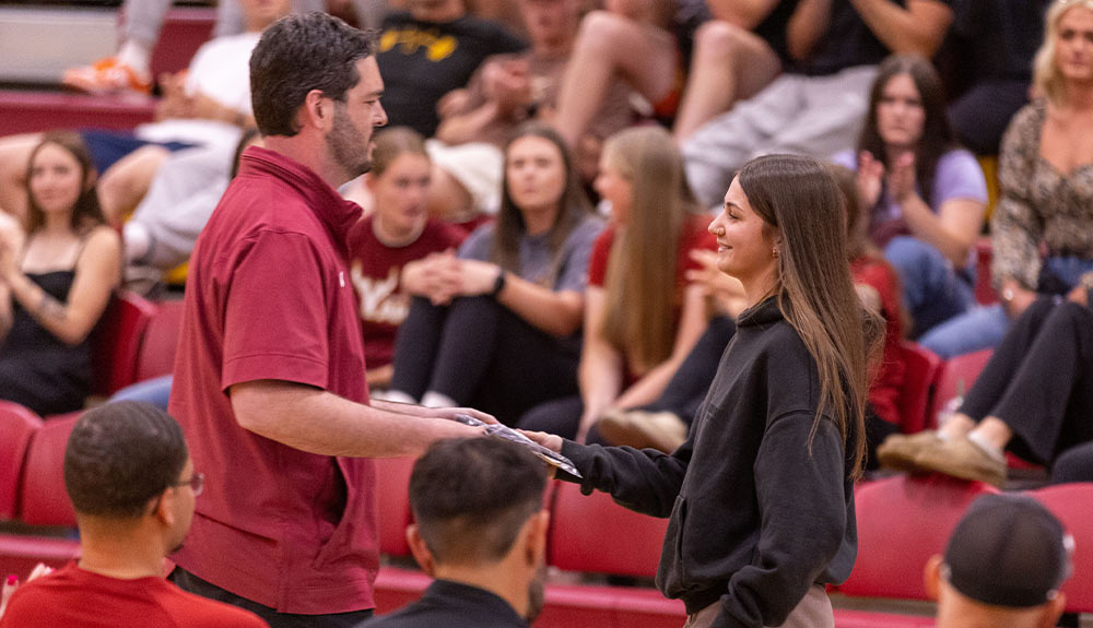 Women's basketball head coach Robin Andrea hands Most Valuable Player Award to Alina Sapilak.