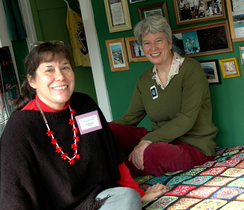 Roxanne Baca & Kathy LaFetra sitting on a quilt at home. 