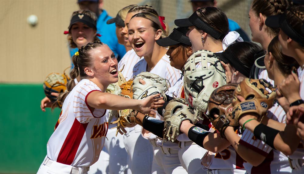 Softball player high fives teammates during player introductions.