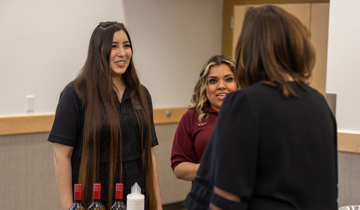 Students talk with a participant at the Grape to Glass Gala