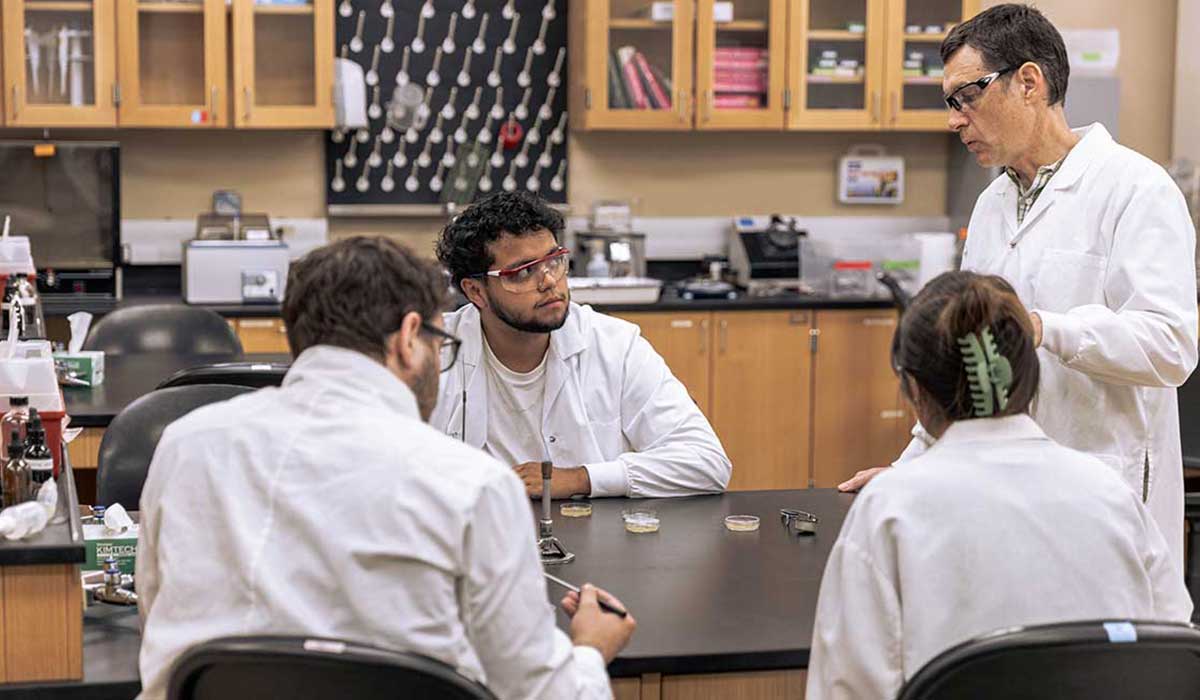 Matthew Loeser works with students in a biology lab