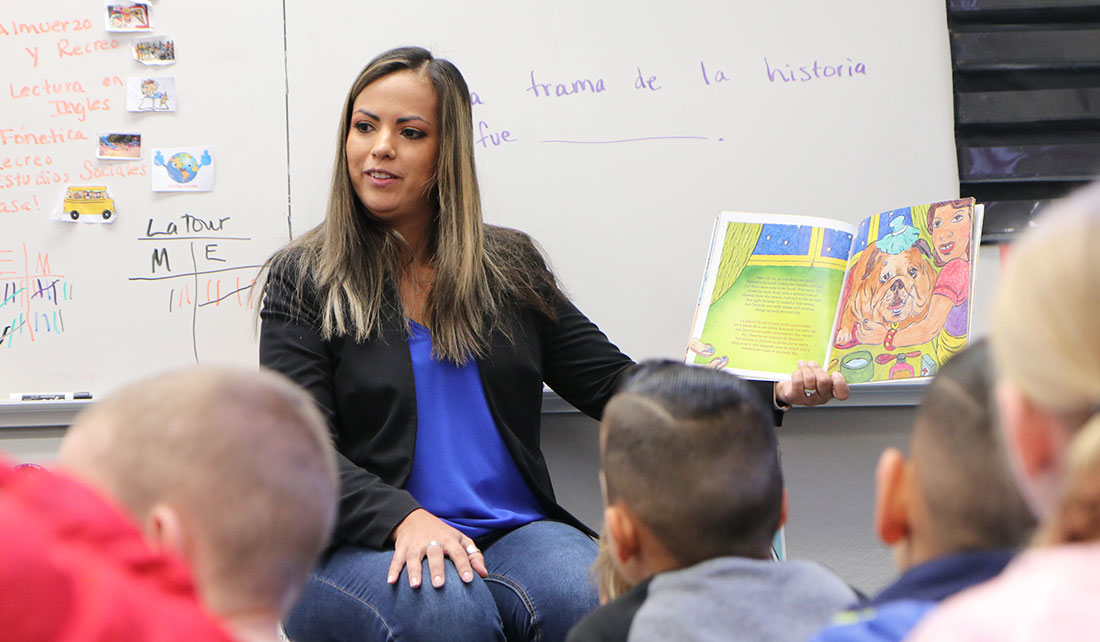 A student teacher reads a book to a class