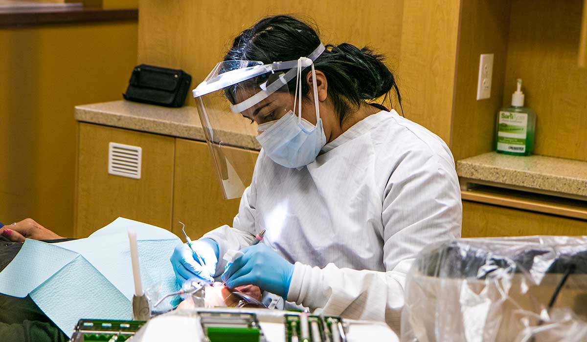 A dental student works on a patient