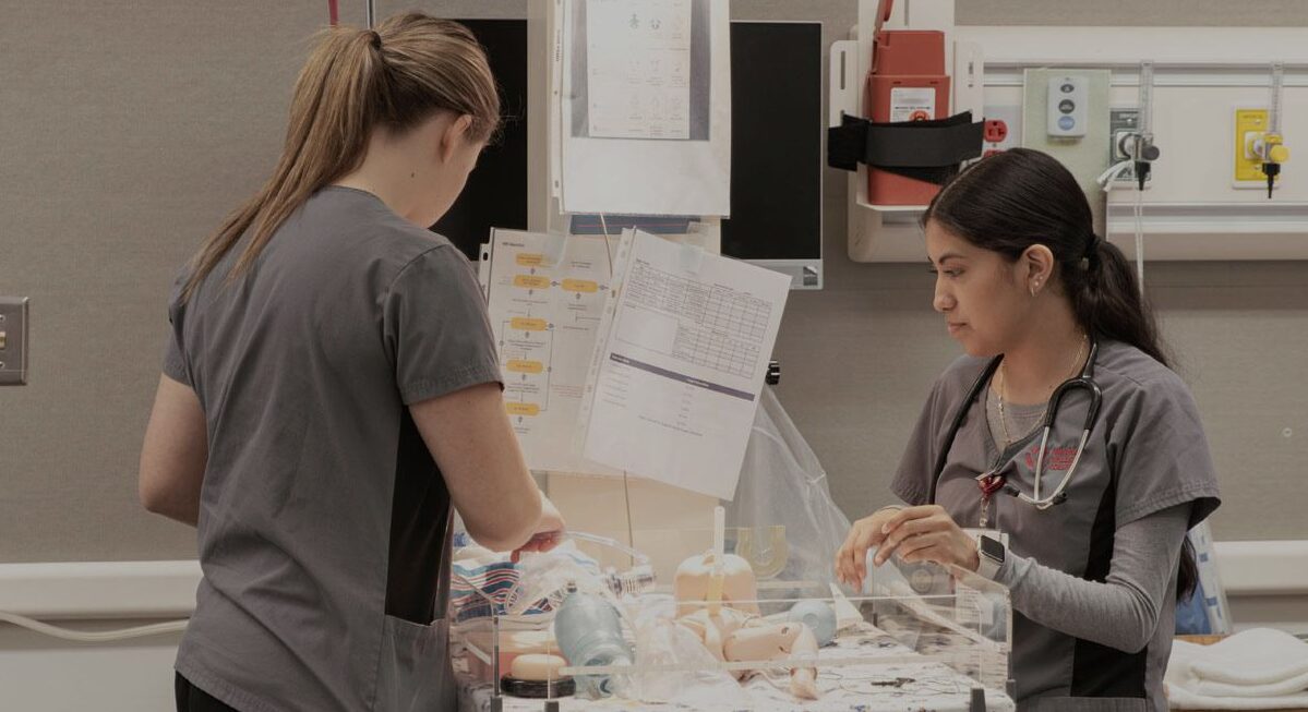 Two nursing students organizing equipment in an operating room. 