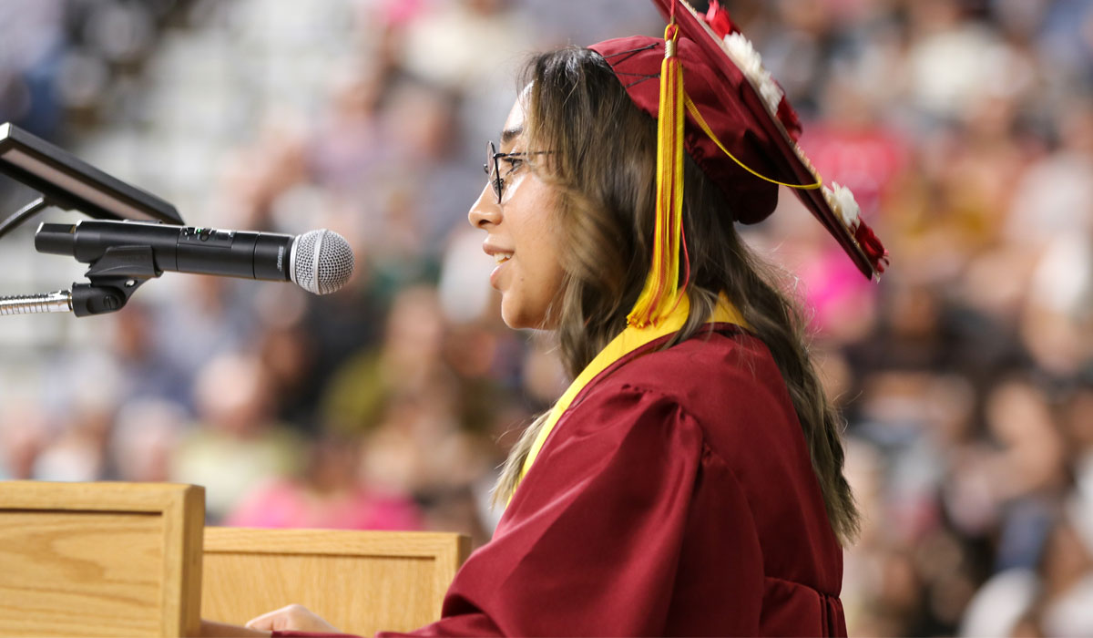 Student dressed in cap and gown speaks at YVC commencement.