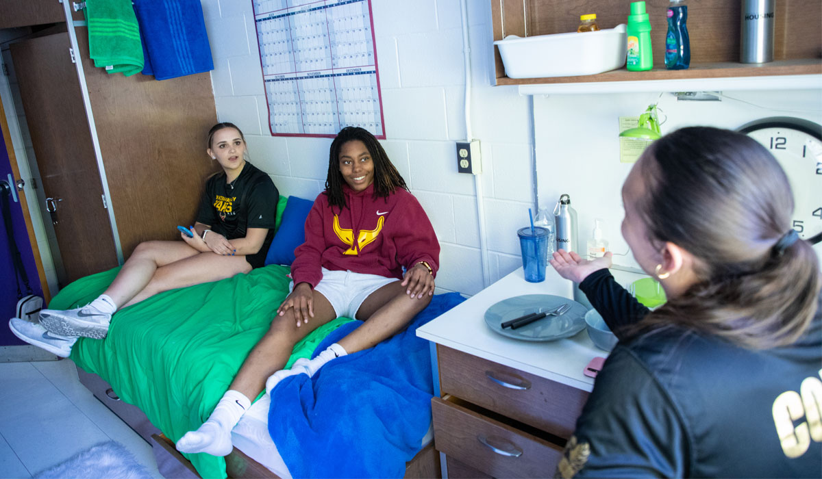 Three students sitting together in a YVC dorm room. 