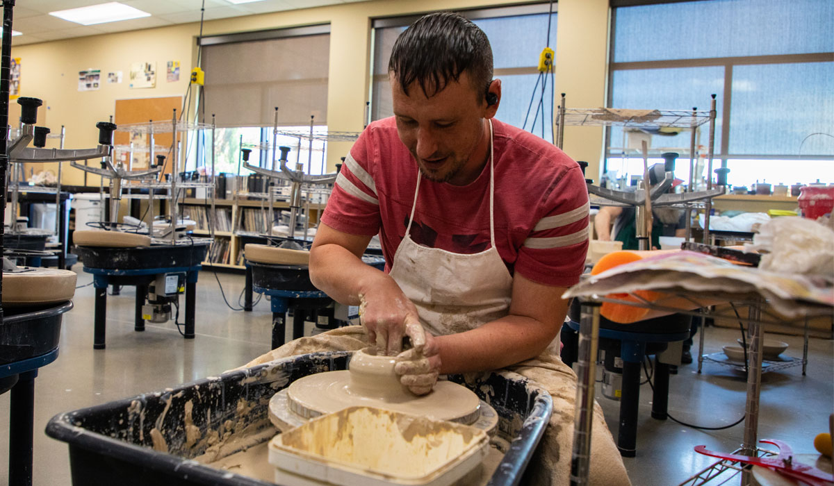 Student working on pottery wheel. 