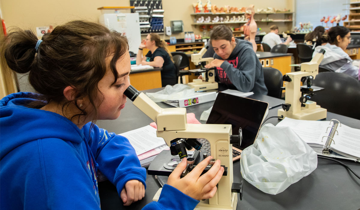 Student works on microscope.