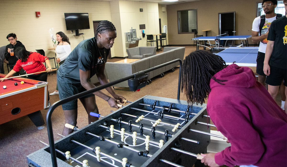 Two student playing fooseball in a common area. 